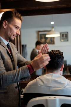 A gentleman barber readies a client's hair for a proper cut.