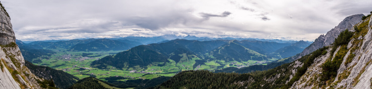 Panorama von Saalfelden am Steinernen Meer und Leogang bis zum Gro&szlig;klockner eingerahmt von den Felsen der Kasawand bei bew&ouml;lktem Himmel