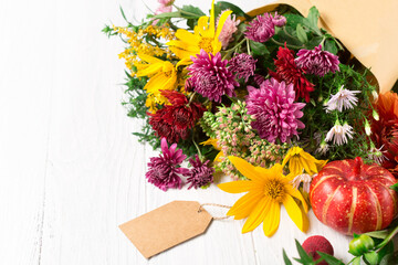 Autumn bouquet of yellow and pink flowers on white wooden background.