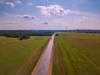 Drone view of the road in the middle of a field on a Sunny day