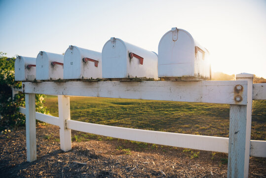White mailboxes attached to a white fence in the countryside