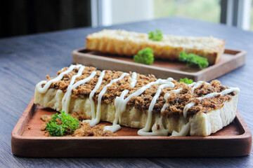 Side view Toast with shredded beef topped with mayonnaise. Served on wooden trays.

