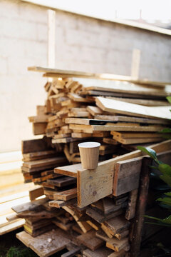 Paper cup on top of wooden planks pile in building site