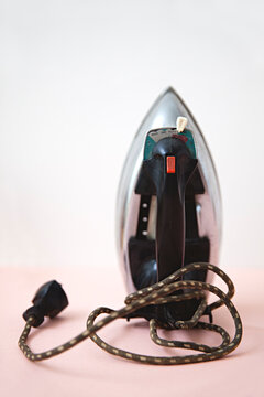 A retro household iron against a pink and white background