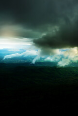 Dramatic dark storm clouds over a green forest.