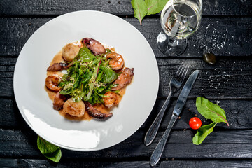 seafood sauce with fresh lettuce in a white plate on a black background

