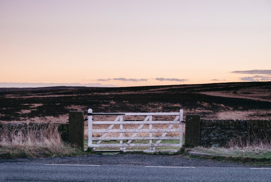White gate leading to moorland at twilight. Derbyshire, UK.