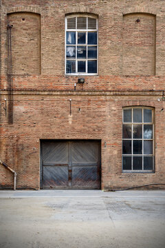 Frontal view of factory facade, old brick wall with windows and wooden door
