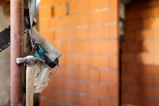 Extreme close up of work tools on belt hanging from iron pole inside house under construction