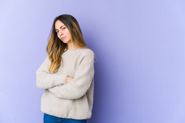 Young caucasian woman isolated on purple background suspicious, uncertain, examining you.