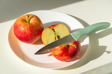Ripe red apples in plate with a knife. Cut an Apple before eating to follow diet or fasting days