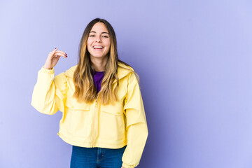 Young caucasian woman isolated on purple background laughing about something, covering mouth with hands.