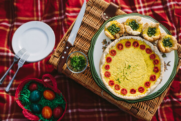 quiche and puff cake filled with cheddar, grated zucchini and cherry tomatoes on colorful picnic place from above