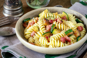 Delicious Italian fusilli pasta with zucchini or courgette and pancetta served in a vintage plate...