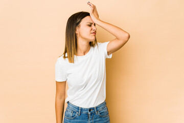 Young woman isolated on beige background forgetting something, slapping forehead with palm and...