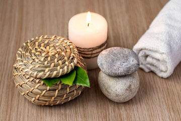 stones, a candle, a jar and green leaves, a white rolled towel. Spa setting concept