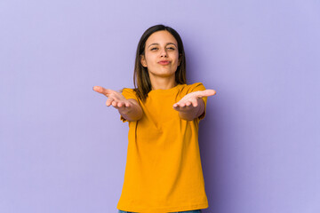 Young woman isolated on purple background folding lips and holding palms to send air kiss.