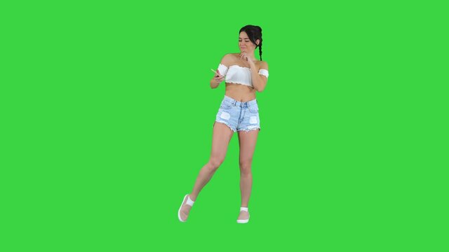 Positivepretty sexy girl listening to music on her phone on a Green Screen, Chroma Key.