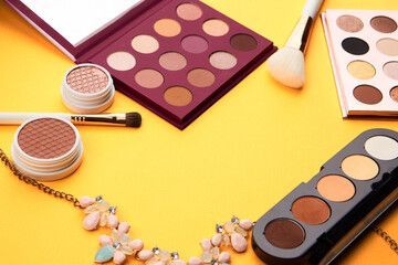 Professional eyeshadows and makeup brushes on a yellow background make-up decoration