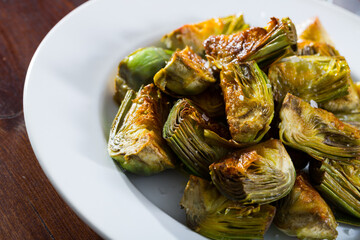 Delicious fried artichoke halves on a white plate. High quality photo