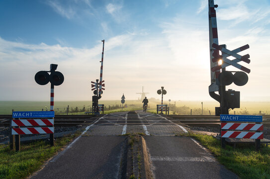 Cyclist passing a railroad crossing on a foggy morning in the countryside.