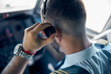 Confident male wearing uniform sitting in the cabin of plane
