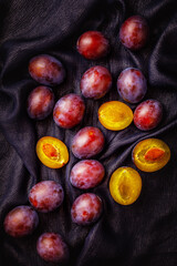 Still life with plums in a bowl on wooden background. Vertical image. Selective focus