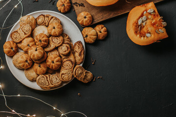 Pumpkin cookies in a plate on a black background. Autumn pastries.