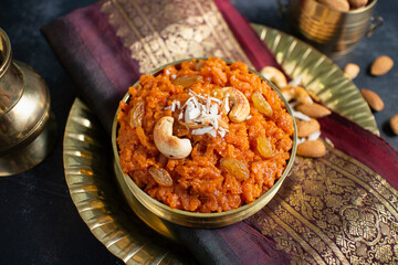 Indian Sweet carrot Halwa or Halva dessert festival sweet served in golden bowl  Mumbai, India for Dussehra, Diwali. Homemade Mithai with dry fruits and cashew nuts in traditional background.