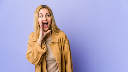 Young blonde woman isolated on purple background shouting excited to front.