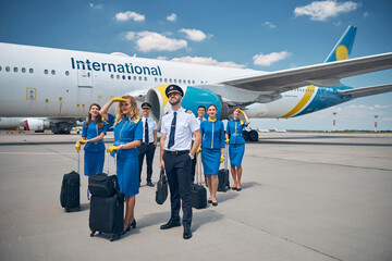 Members of aircrew with travel bags standing outdoors in airfield