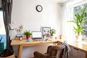 Interior of busniess room with wooden office desk with window and empty screen of laptop. Technology and home office with white wall and copy space. 