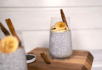 Chia seeds pudding with banana, cinnamon and yougurt on white wooden textured background