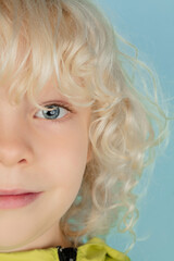 Look. Close up portrait of beautiful caucasian little boy isolated on blue studio background. Blonde curly male model. Concept of facial expression, human emotions, childhood, ad, sales.