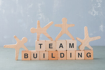 Team building concept with wooden blocks, wooden human figures on it on sage color background side view. horizontal image