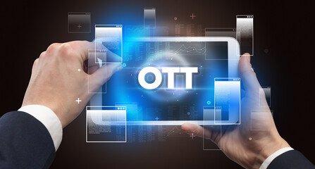 Close-up of a hand holding tablet with OTT abbreviation, modern technology concept
