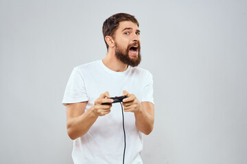 Naklejka premium A man with a gamepad in his hands playing games leisure lifestyle technology white t-shirt light background