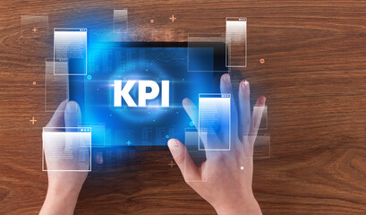 Close-up of a hand holding tablet with KPI abbreviation, modern technology concept