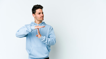 Young caucasian man isolated on white background showing a timeout gesture.