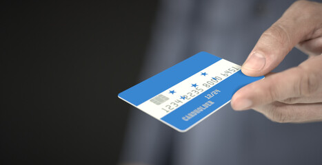 Man offers plastic bank card with printed flag of Honduras Fictional numbers