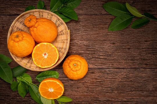 Fresh Orange fruit in a basket, Top view Dekopon orange or sumo mandarin tangerine on wood background.