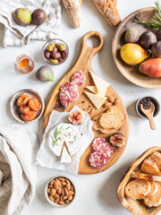 Snack set table. Variety of cheese, olives, sausage, baguette slices, figs on wooden board grey background, Flat lay. Top view.