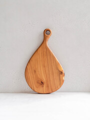 Wooden cutting board layout against the gray wall. Minimal kitchen concept. copy space