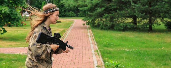 Teenage girl playing in lasertag shooting game in open air. Weapon in the hands of people. War simulation. Banner.