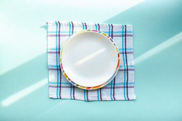 white empty plate on a blue background, covered with the rays of the morning sun
