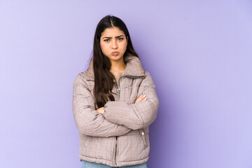 Obraz premium Young indian woman isolated on purple background blows cheeks, has tired expression. Facial expression concept.