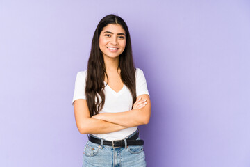 Young indian woman isolated on purple background who feels confident, crossing arms with...