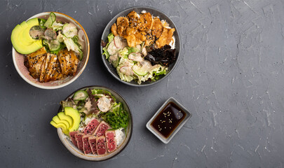 Hawaiian dish. Three types of Poke salad with chicken, eel and tuna, rice and Chuka seaweed in a deep bowl on a gray background. No people. Copy space. Top view