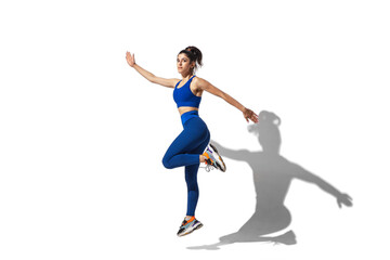 Fototapeta na wymiar Energy. Beautiful young female athlete practicing on white studio background, portrait with shadows. Sportive fit model in motion and action. Body building, healthy lifestyle, style concept.