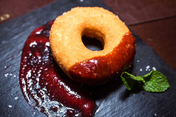 Fresh donut with red sugar jam on black background